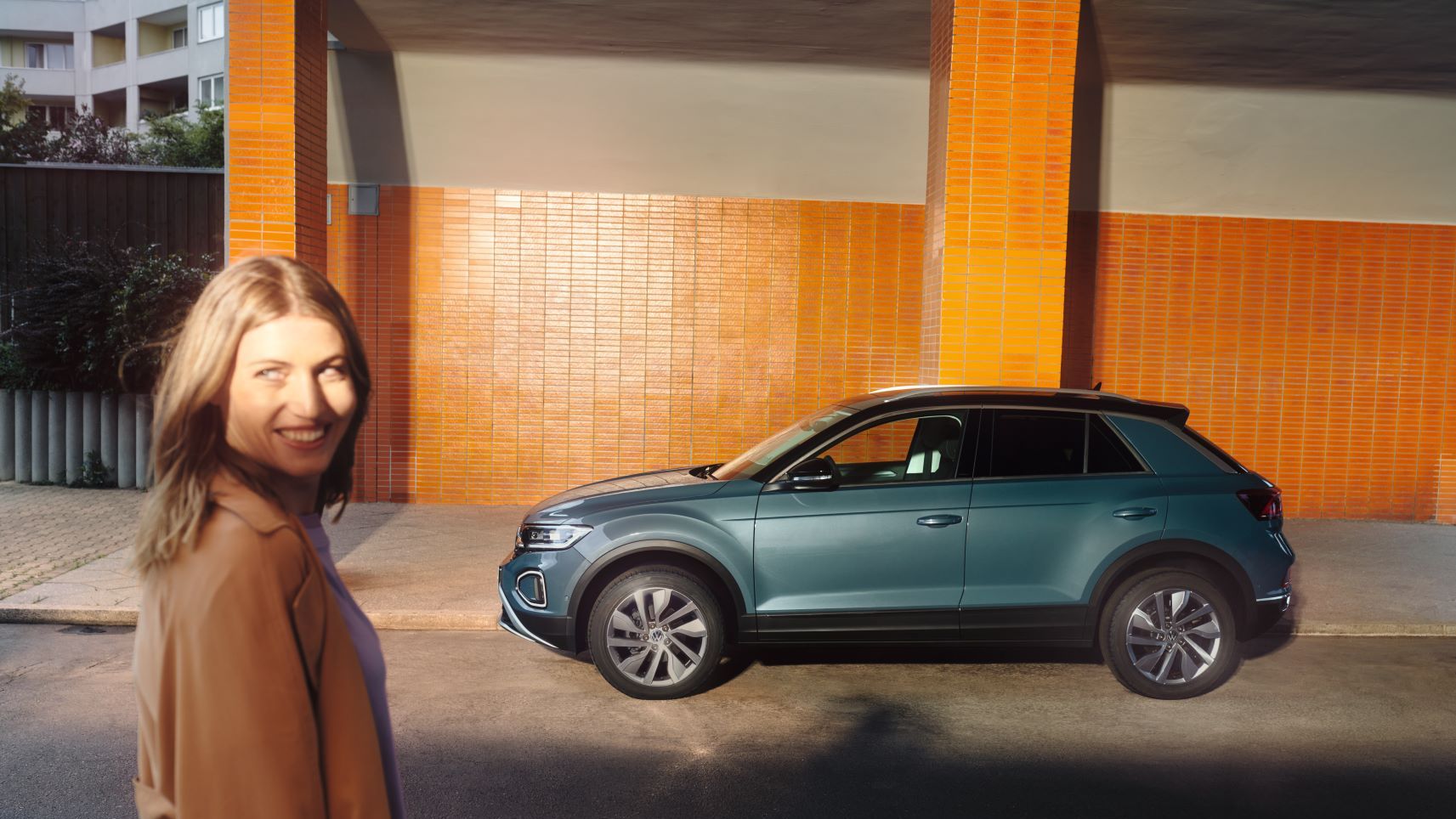 VW T-Roc Style, seitliche Ansicht, Frau steht daneben und lächelt