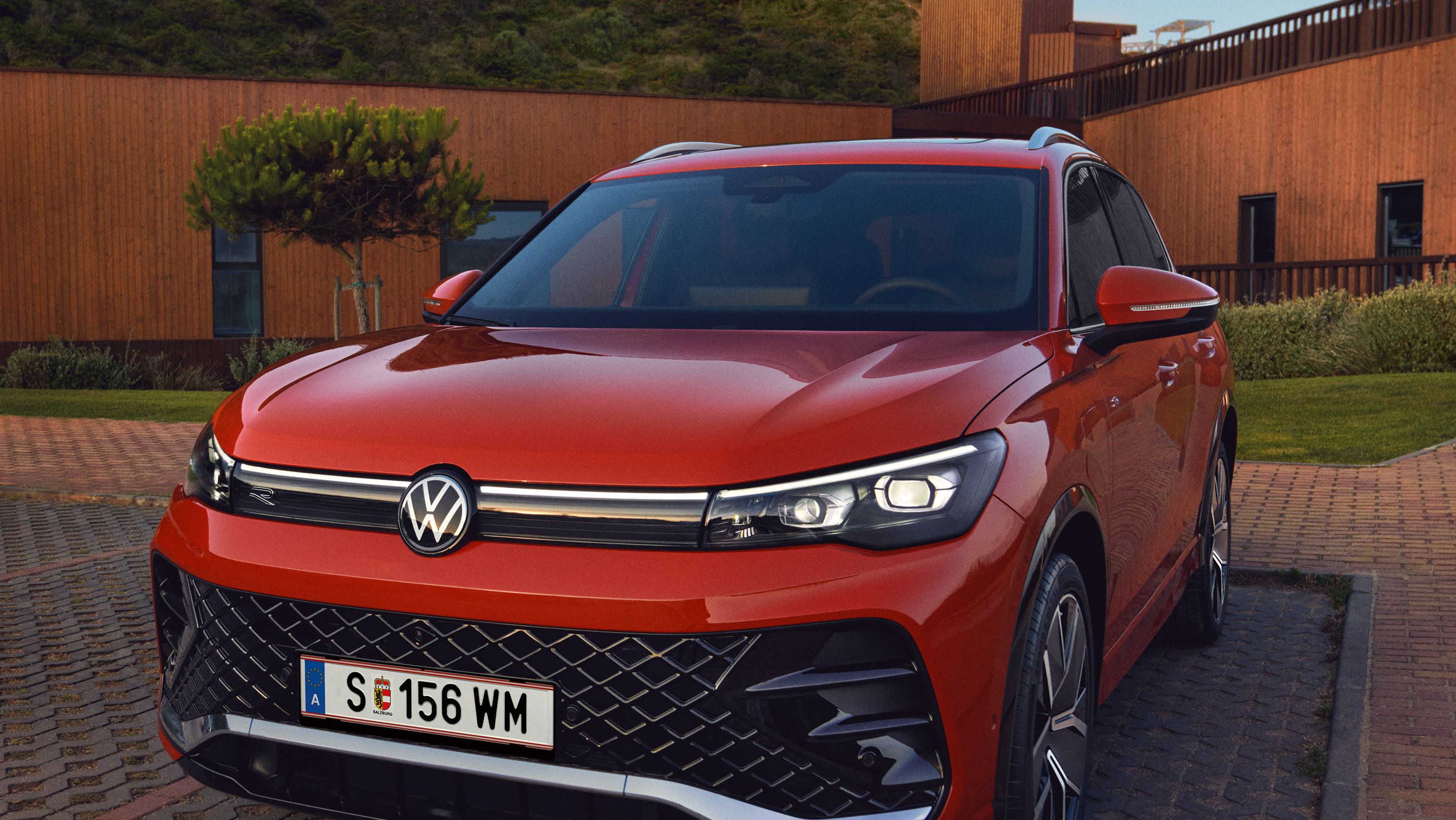 Detailansicht der Front-Lichtsignatur eines auf einem Parkplatz stehenden roten VW Tiguan.
