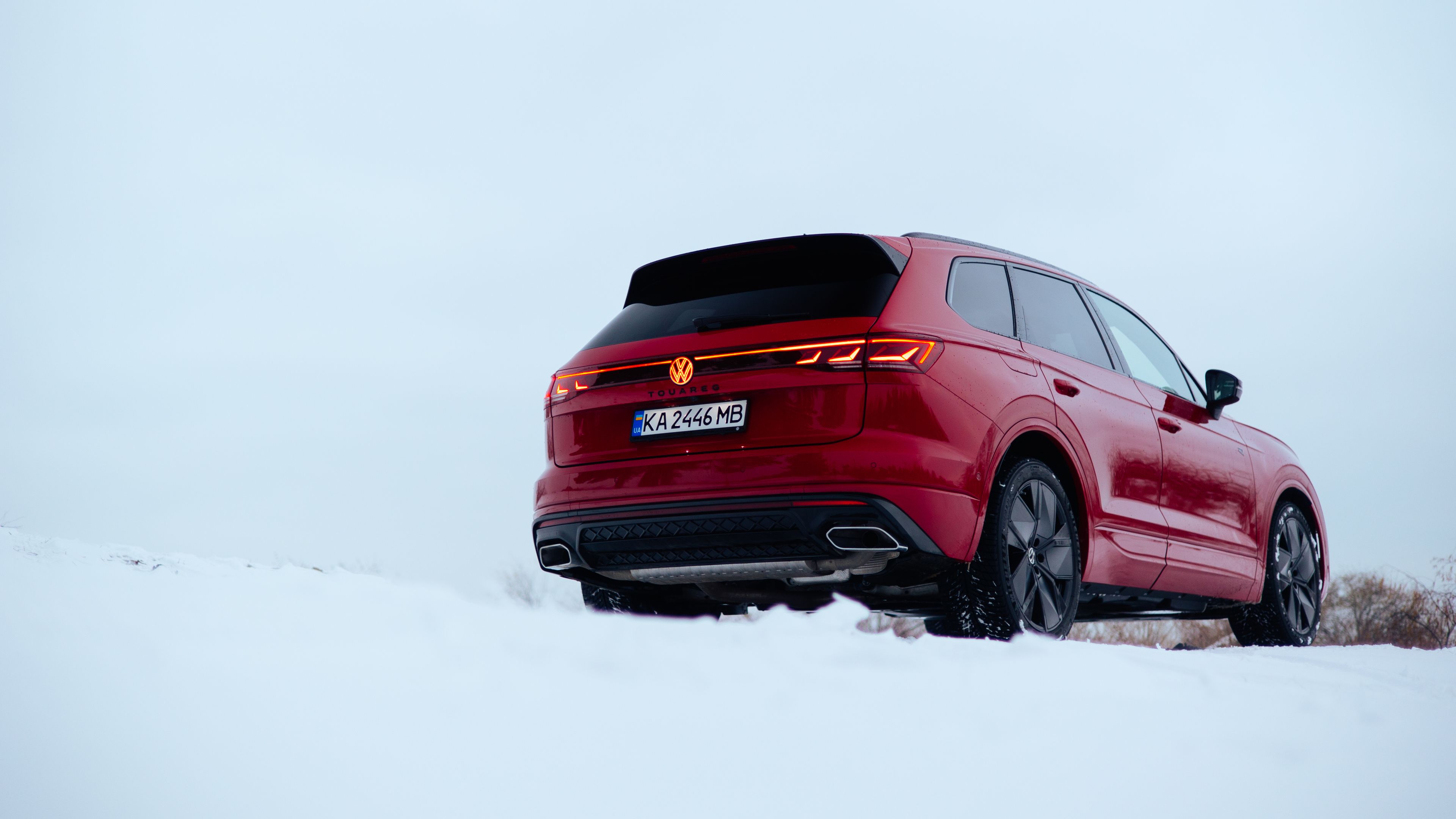 Ein Mann überquert die Straße, schräg hinter ihm ein am Straßenrand parkender VW Touareg R-Line.