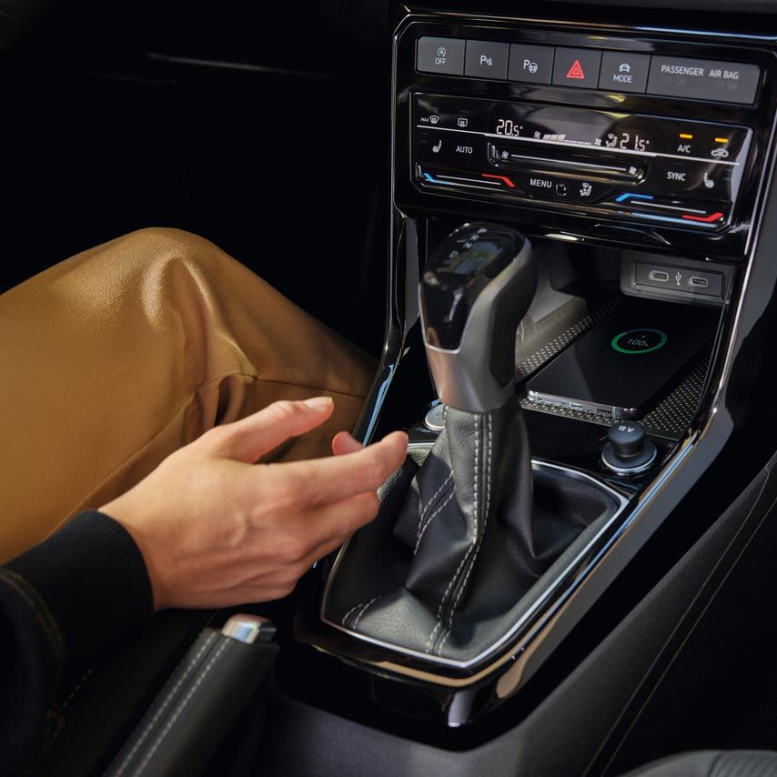 Ein Smartphone lädt im vordersten Fach der Mittelkonsole durch das Wireless Charging Pad im VW T-Cross.