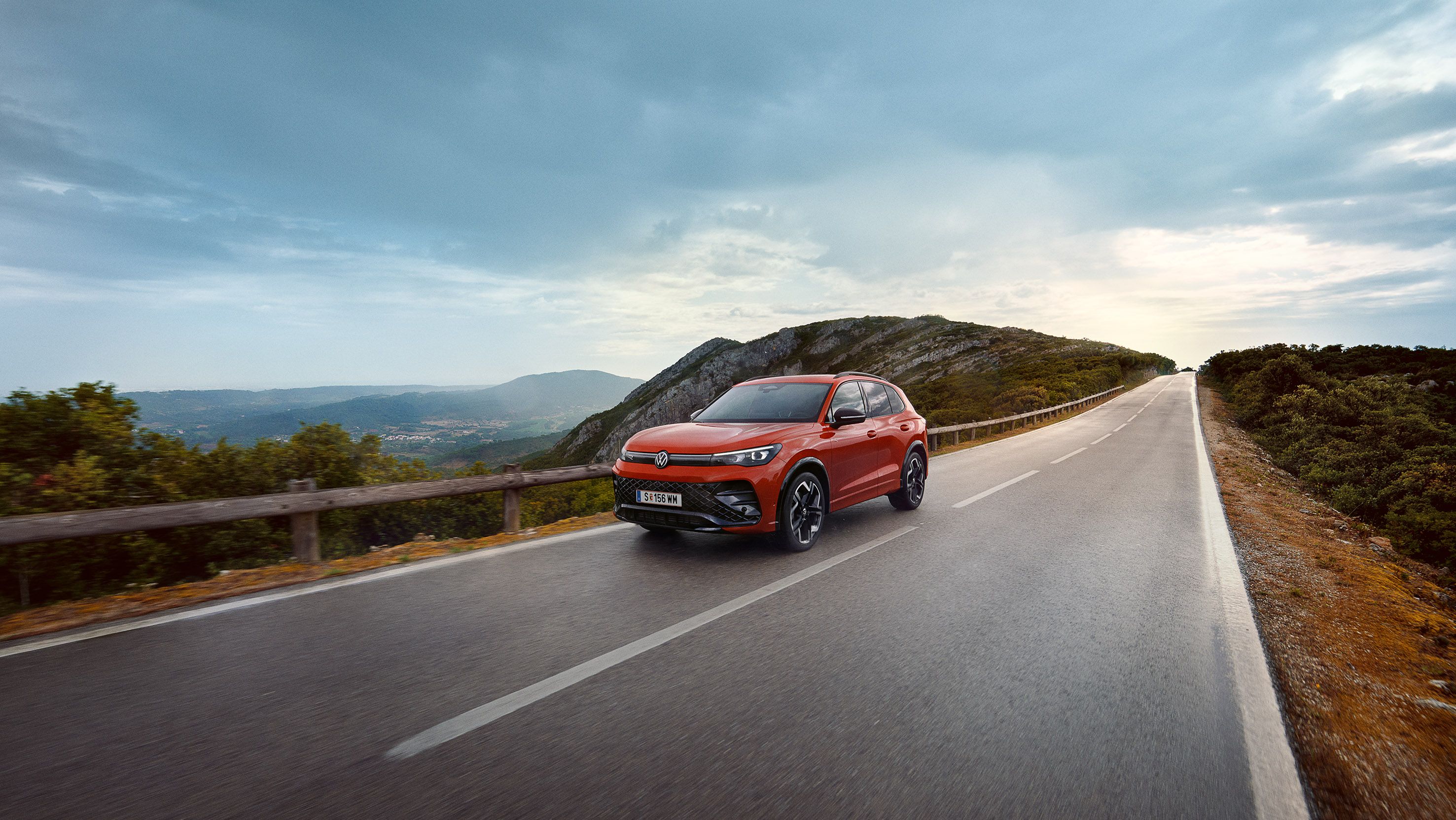 Roter VW Tiguan fährt eine Straße entlang.